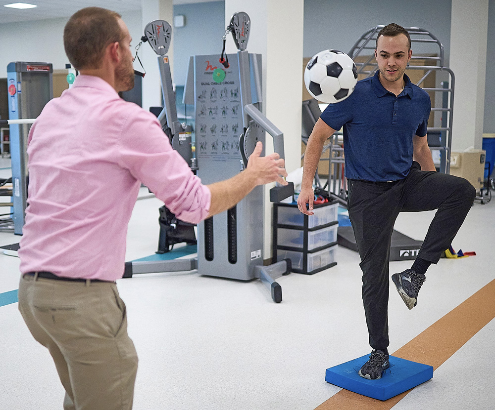 Patient and therapist performing therapy with a soccer ball 