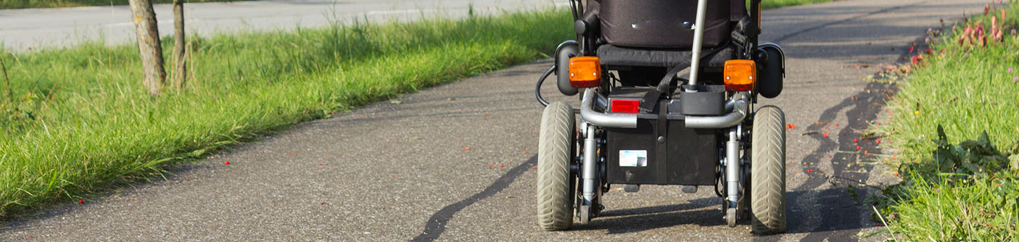 Man in an electric wheelchair on a sidewalk.