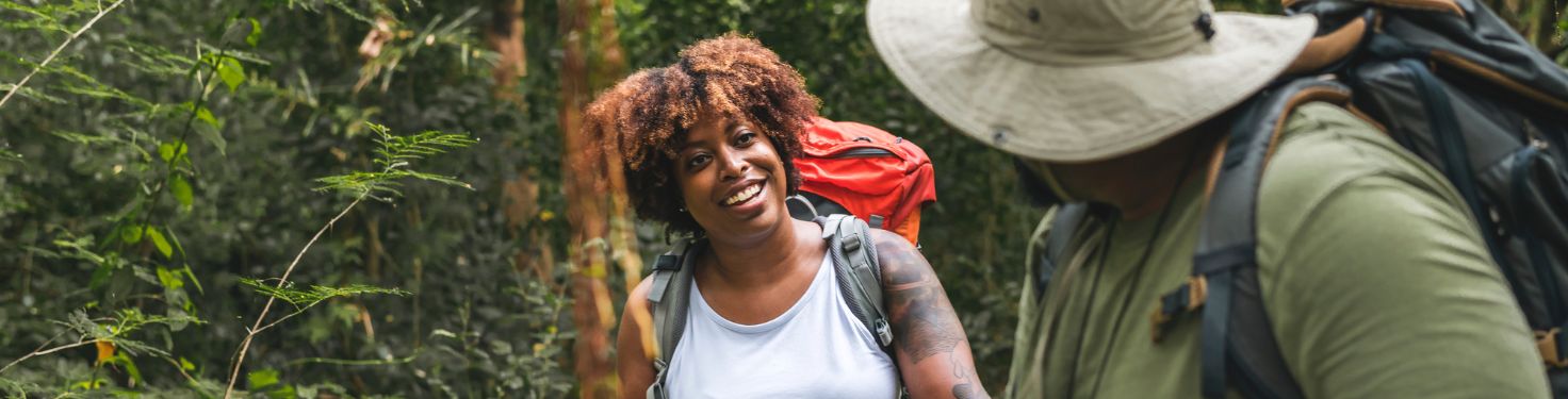 Two people hiking outdoors, one is smiling at the other