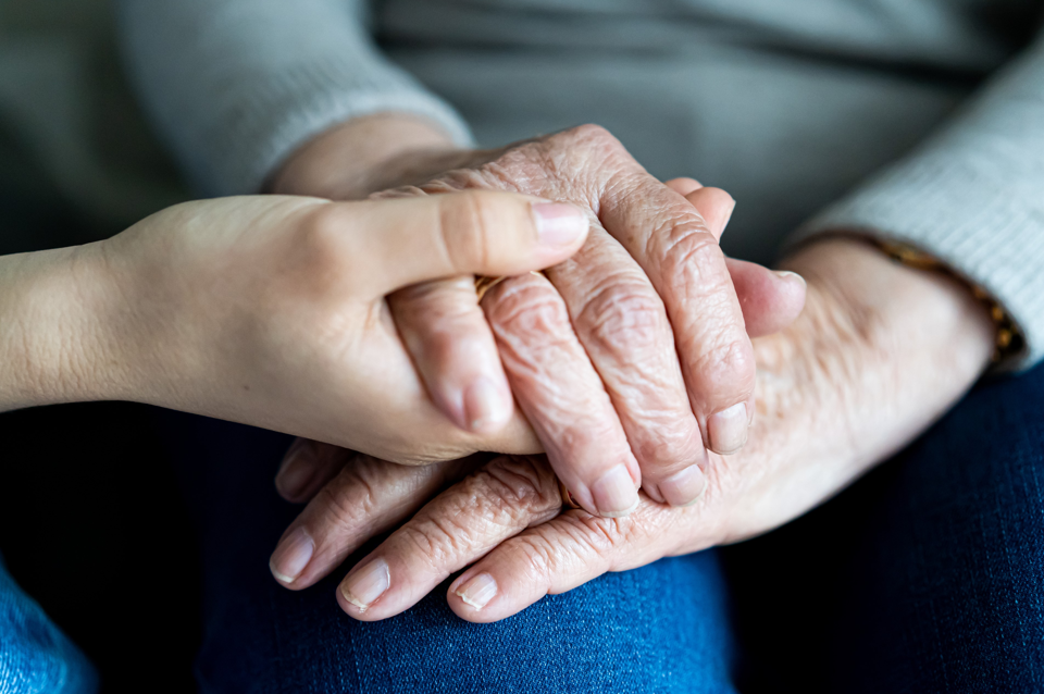 elderly hands in hands of a younger person offering support for one another
