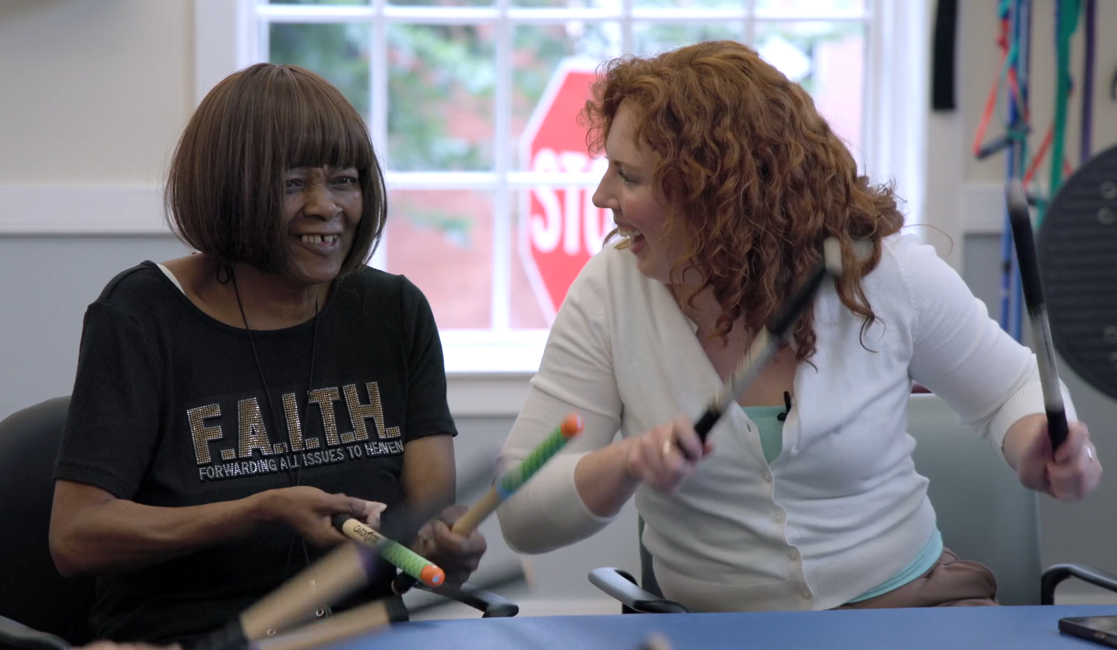 A philly power hour member and physical therapist, casey, drumming with drumsticks and smiling