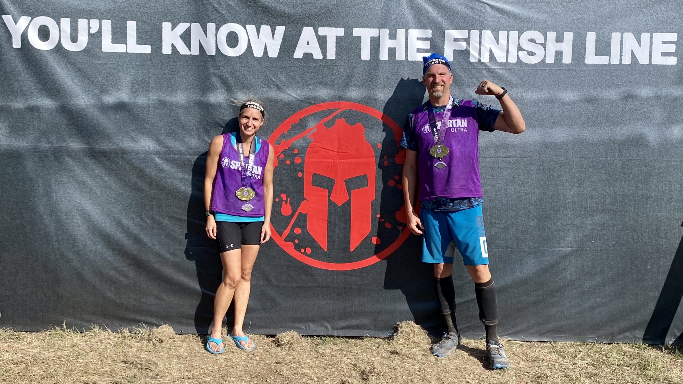 Andrea Wonderlin at a Spartan race with her husband posing and smiling for a photo