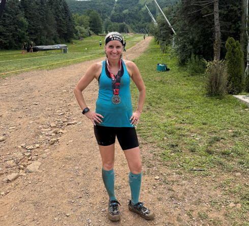 Andrea Wonderlin standing on the course of a Spartan race smiling and posing for a photo